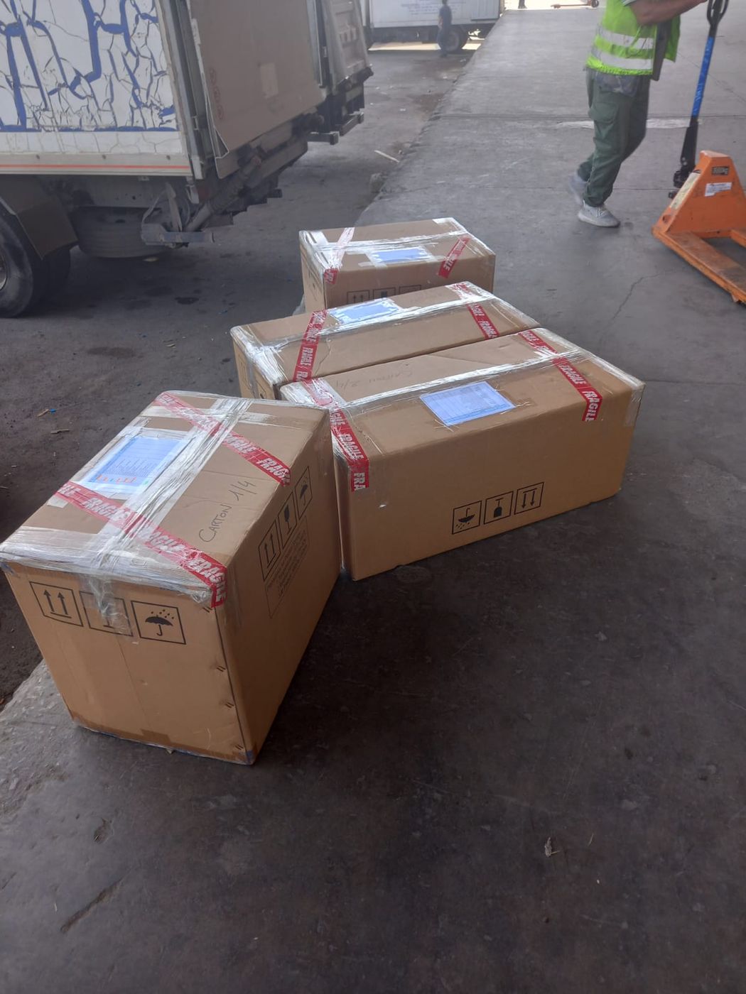 Four wrapped cartons marked fragile, lined up on a loading dock before pickup.